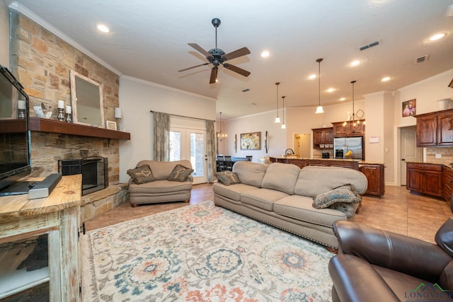 living area featuring ornamental molding, visible vents, light tile patterned flooring, and a stone fireplace