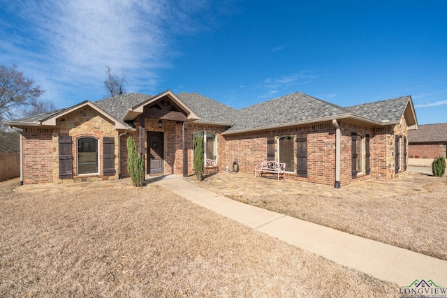 ranch-style home with brick siding and roof with shingles