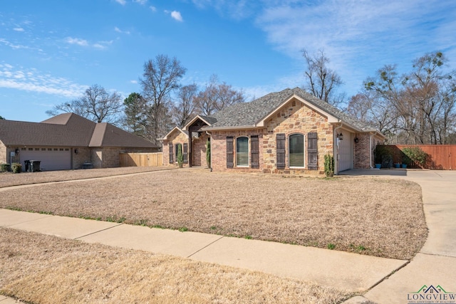 ranch-style home featuring an attached garage, brick siding, fence, concrete driveway, and stone siding