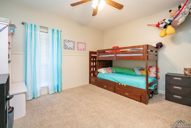 bedroom with light carpet, a ceiling fan, and wainscoting