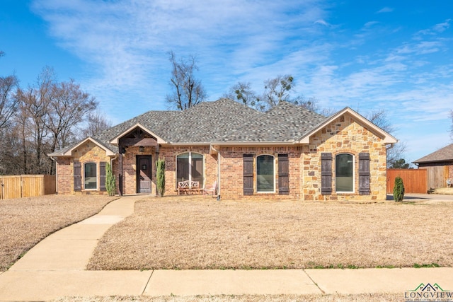 ranch-style house with brick siding, roof with shingles, and fence