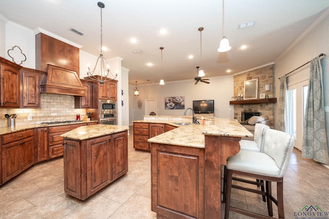 kitchen with a sink, stainless steel appliances, a large island with sink, and hanging light fixtures