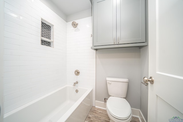 bathroom featuring hardwood / wood-style floors, tiled shower / bath combo, and toilet