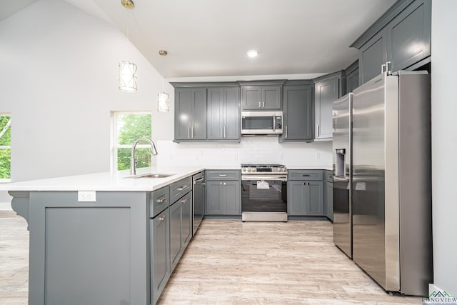 kitchen with gray cabinetry, pendant lighting, sink, kitchen peninsula, and stainless steel appliances