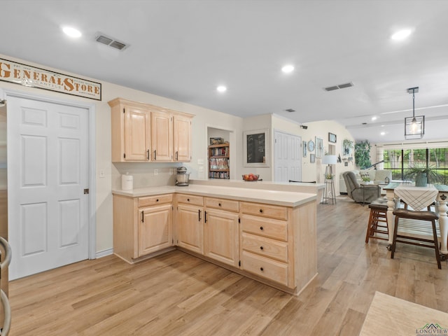 kitchen featuring light countertops, light brown cabinetry, a peninsula, and visible vents