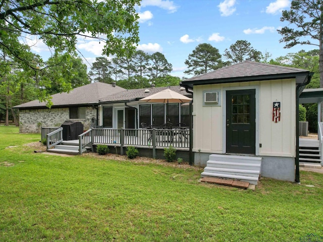 back of house with a lawn, a deck, and roof with shingles