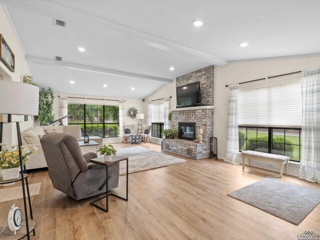 living room featuring lofted ceiling with beams, a brick fireplace, wood finished floors, and visible vents
