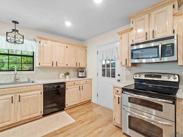 kitchen featuring light brown cabinetry, appliances with stainless steel finishes, a sink, light countertops, and light wood-style flooring