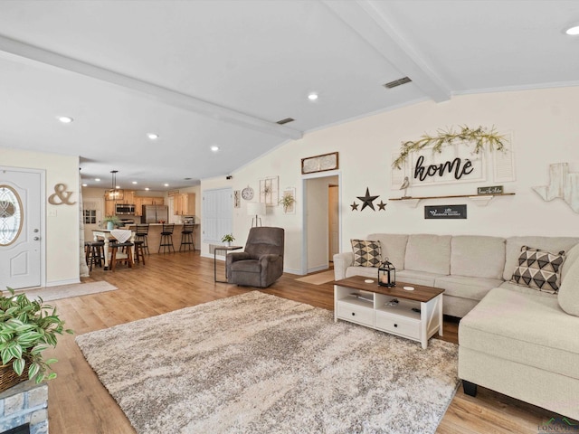 living room featuring lofted ceiling with beams, light wood-style flooring, and visible vents