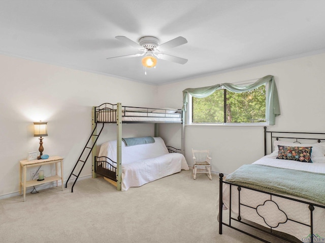 carpeted bedroom featuring baseboards, ornamental molding, and ceiling fan