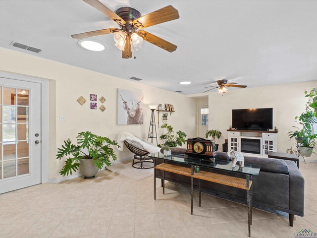 living room featuring baseboards, ceiling fan, and visible vents