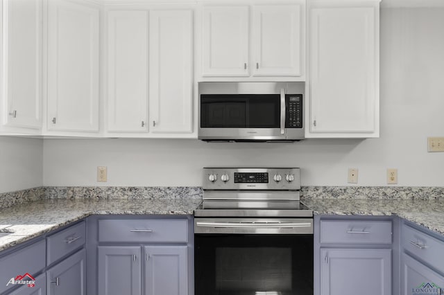 kitchen featuring light stone counters, appliances with stainless steel finishes, and white cabinets