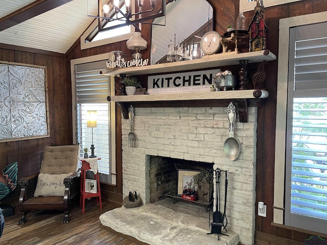 living room with wood walls, lofted ceiling, a chandelier, wood finished floors, and a fireplace with raised hearth