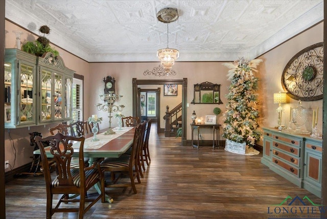 dining space featuring an ornate ceiling, dark wood-type flooring, a chandelier, ornamental molding, and baseboards