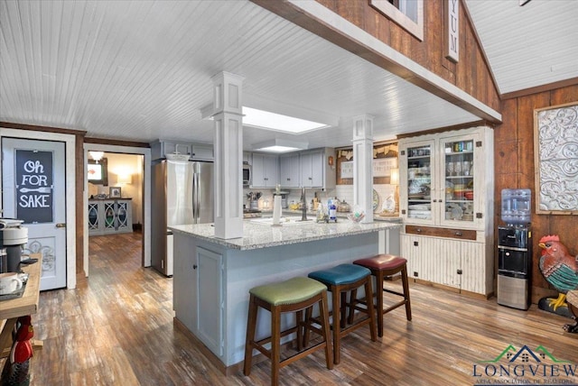 kitchen featuring ornate columns, washing machine and dryer, dark wood-style floors, and wooden walls