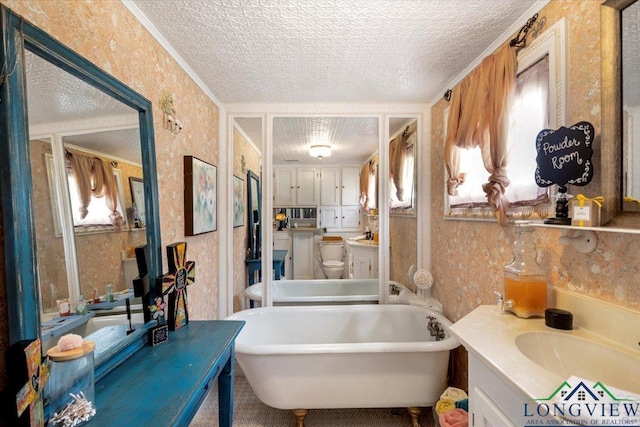 bathroom with wallpapered walls, a textured ceiling, a freestanding tub, and vanity