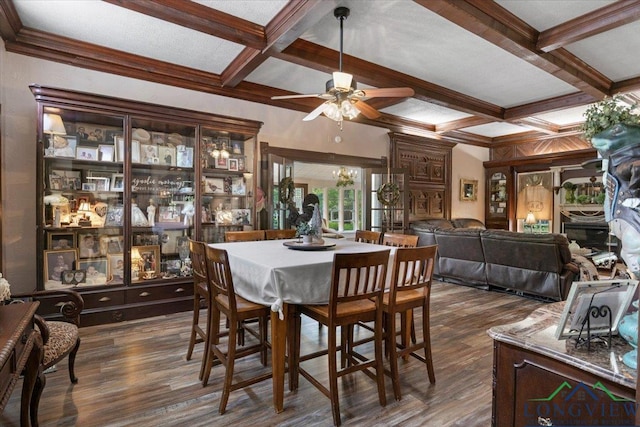 dining space with coffered ceiling, beam ceiling, dark wood-type flooring, ceiling fan, and crown molding