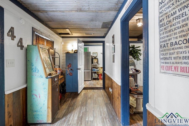 hallway featuring wood finished floors, wood walls, and wooden ceiling