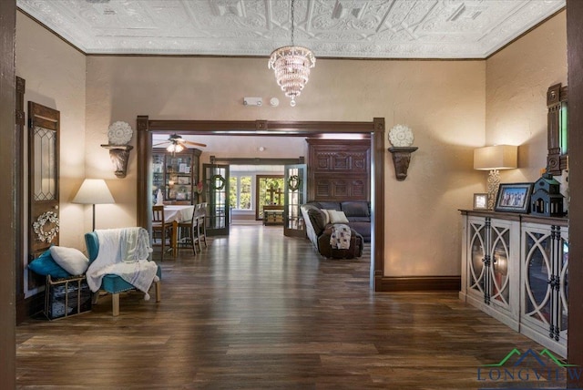 hallway featuring an ornate ceiling, wood finished floors, ornamental molding, a textured wall, and a chandelier
