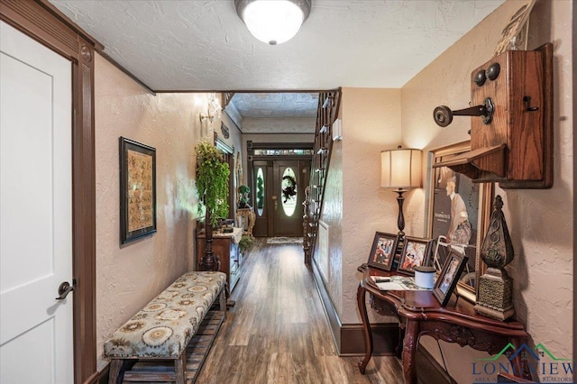 hall with a textured wall, wood finished floors, a textured ceiling, and baseboards