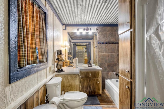 bathroom with toilet, a bathtub, vanity, and wood finished floors