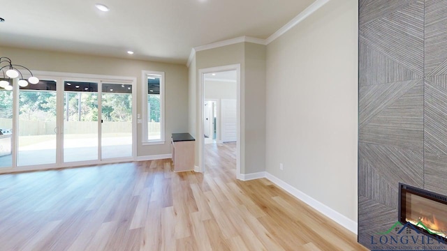 2510 Windmill Ln, Longview, TX 75601 - unfurnished living room with baseboards, light wood-style flooring, crown molding, a glass covered fireplace, and recessed lighting