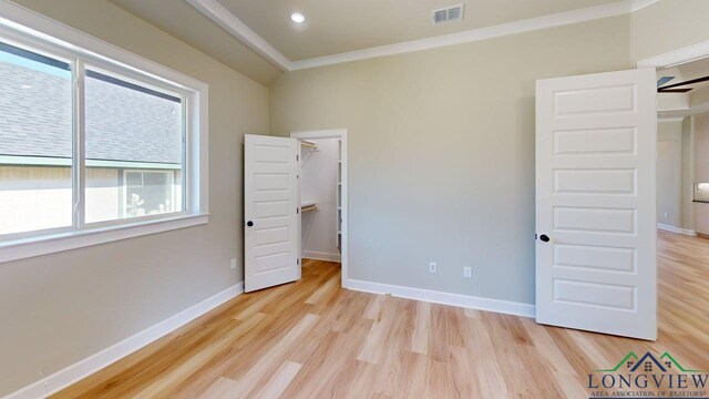 2510 Windmill Ln, Longview, TX 75601 - unfurnished bedroom with multiple windows, light wood-style floors, crown molding, a walk in closet, and recessed lighting