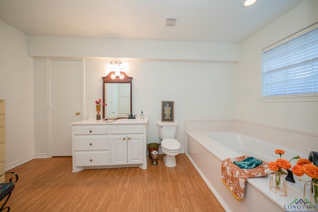 bathroom with hardwood / wood-style floors, vanity, toilet, and a tub to relax in