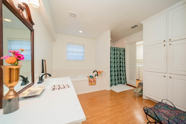 bathroom with hardwood / wood-style floors, vanity, washer / dryer, and plus walk in shower