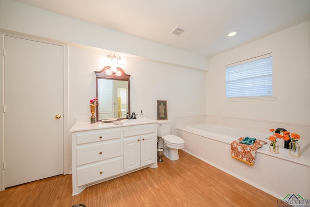 bathroom featuring a bath, wood-type flooring, vanity, and toilet