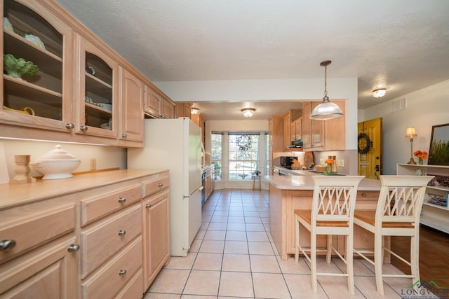 kitchen featuring light brown cabinets, light tile patterned floors, white fridge, and decorative light fixtures