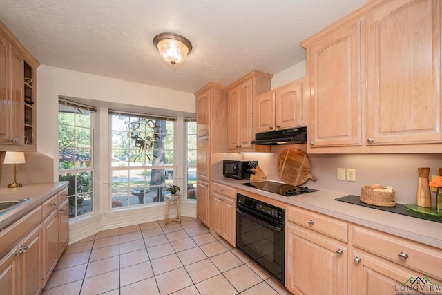 kitchen with black appliances, light tile patterned floors, a textured ceiling, and light brown cabinetry