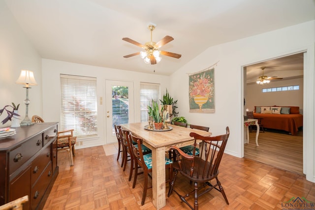 dining room featuring ceiling fan, light parquet flooring, and vaulted ceiling