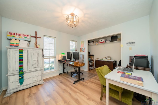 office with light hardwood / wood-style flooring and a notable chandelier