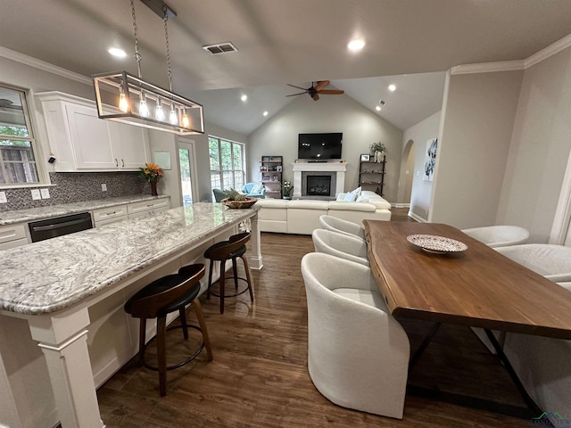 kitchen with a center island, visible vents, white cabinetry, ceiling fan, and a fireplace