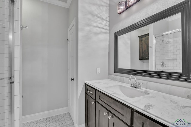 full bath featuring tile patterned flooring, vanity, ornamental molding, baseboards, and tiled shower