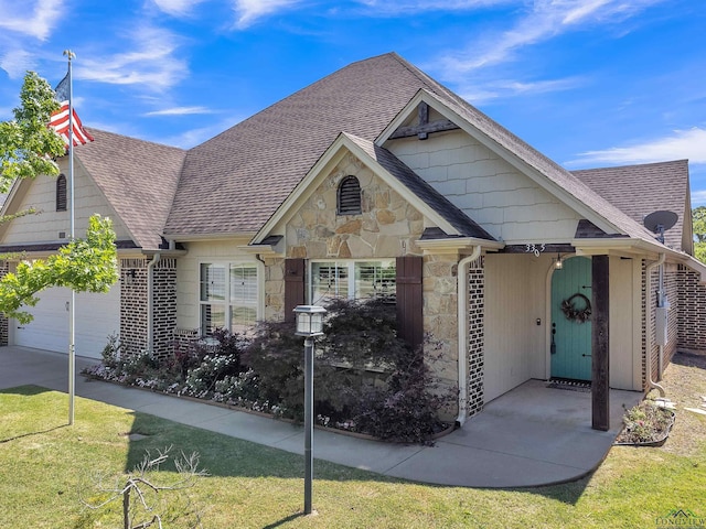 view of front facade with roof with shingles, stone siding, driveway, and a garage