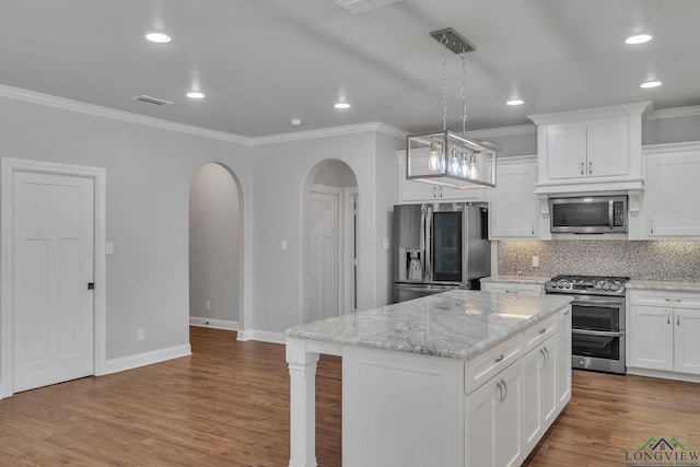 kitchen with ornamental molding, arched walkways, and appliances with stainless steel finishes
