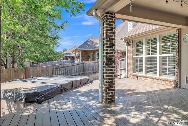 deck featuring fence and a covered hot tub