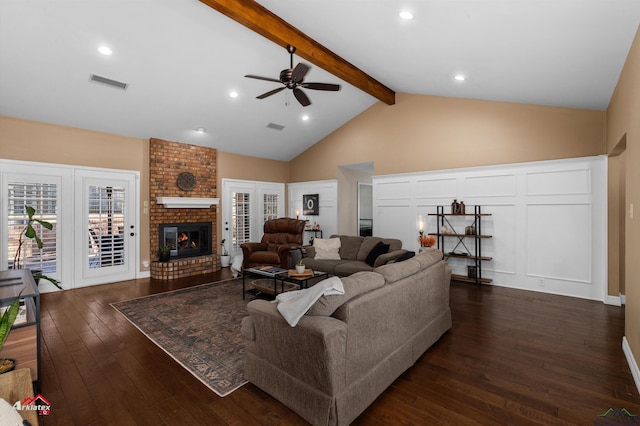 living room with ceiling fan, dark wood-type flooring, lofted ceiling with beams, and a brick fireplace