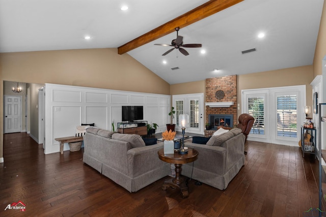 living room with beamed ceiling, ceiling fan, a fireplace, and dark wood-type flooring