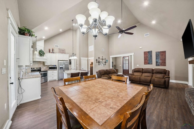 dining room featuring ceiling fan with notable chandelier, dark hardwood / wood-style flooring, and a towering ceiling