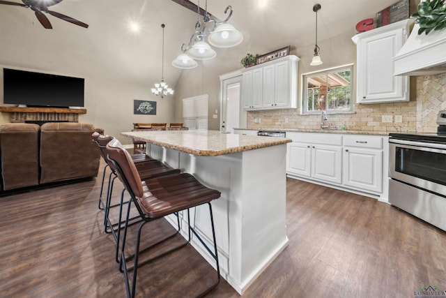 kitchen featuring stainless steel electric stove, white cabinetry, a center island, and decorative light fixtures