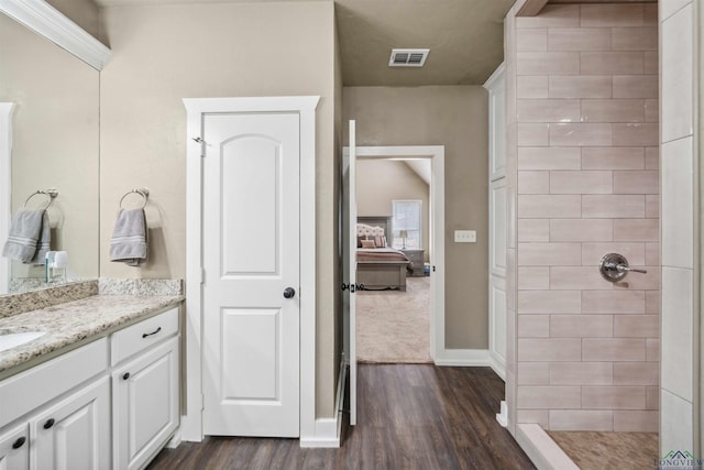 bathroom featuring vanity, wood-type flooring, and tiled shower