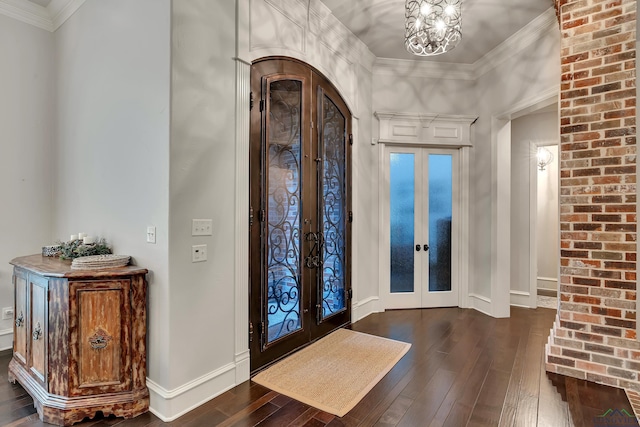 entrance foyer with french doors, dark wood-type flooring, ornamental molding, and a notable chandelier