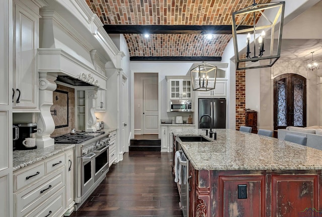 kitchen featuring appliances with stainless steel finishes, brick ceiling, a spacious island, sink, and pendant lighting