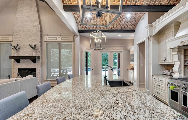 kitchen with range with two ovens, a fireplace, decorative light fixtures, light stone counters, and brick ceiling