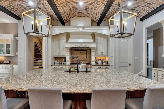 kitchen with a kitchen breakfast bar, brick ceiling, vaulted ceiling, a spacious island, and hanging light fixtures