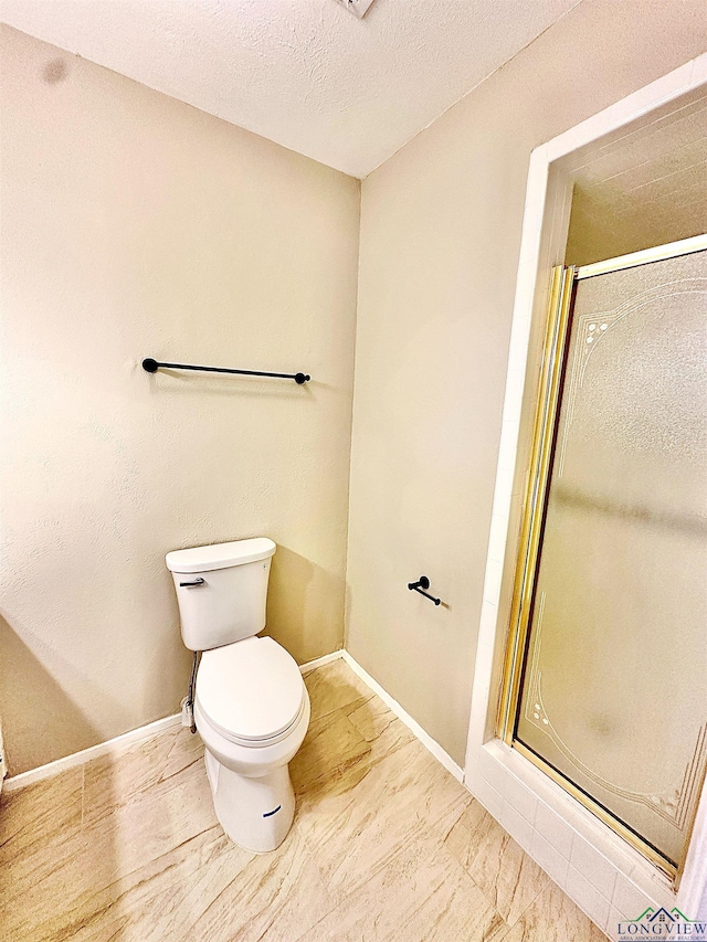 bathroom with a textured ceiling, toilet, and walk in shower