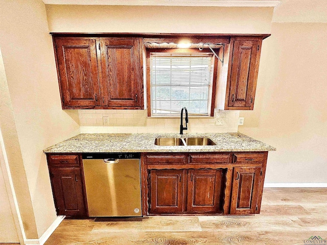 kitchen featuring tasteful backsplash, dishwasher, sink, and light wood-type flooring